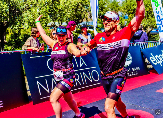 A man and woman happily running, both are dressed in athletic wear, smiling and appearing energetic as they move along the track
